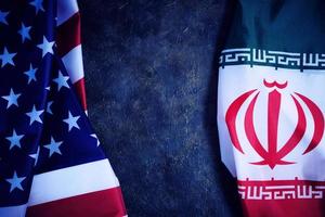 Flags of Iran and United States of America are opposite each other dark background. photo