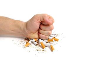 Man crushes cigarettes with his fist refusing to smoke.On white background.