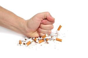 el hombre aplasta los cigarrillos con el puño negándose a fumar. sobre fondo blanco.