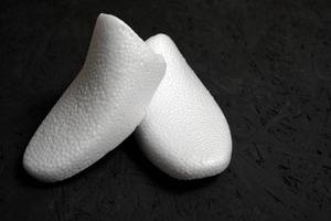 forma de zapato hecha de espuma blanca sobre un fondo negro.