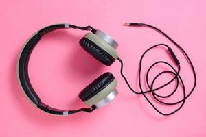 auriculares con cable en color caqui sobre un fondo rosa. foto