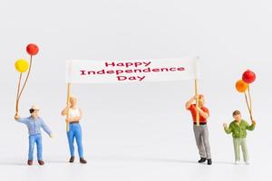 Miniature people holding flags with word Happy Independence day photo