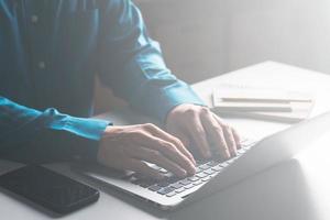 los hombres de negocios trabajan en computadoras y escriben en un bloc de notas con un bolígrafo para calcular los estados financieros dentro de la empresa. foto