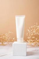 Cream tube mockup for branding presentation. Natural skincare beauty product on square white podium. Natural earthy colors photo