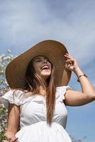 Young caucasian woman enjoying the flowering of an apple trees laughing photo