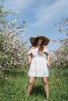 joven mujer caucásica disfrutando del florecimiento de un manzano