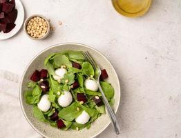 Beetroot, mozzarella and arugula salad with pine nuts top view