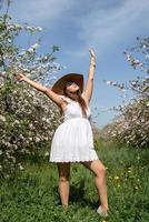 Young caucasian woman enjoying the flowering of an apple trees photo