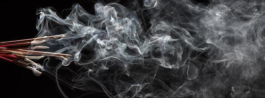 Creative illustration of incense stick aroma with smoke isolated on black background photo