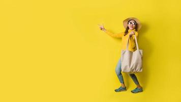 retrato de una hermosa niña emocionada con vestido y gafas de sol con bolsas de la compra. alegre joven con bolso sobre fondo amarillo. moda de compras adicta a las compras. foto