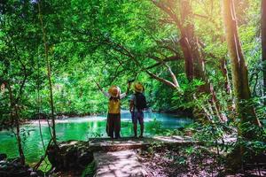 Travelers, couples with natural travel backpacks during the holidays. Couples traveling, relaxing in greens jungle and enjoying  the beautiful Emerald pond. Tourism, hiking, nature study. photo