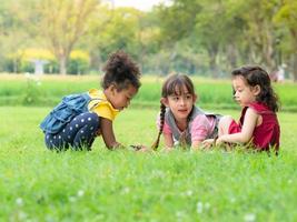 un grupo de niños pequeños de muchas nacionalidades juegan y aprenden fuera de la escuela foto