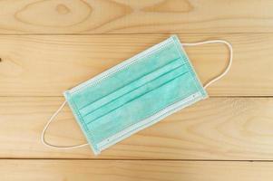 Surgical mask with rubber ear straps on wood background.Protection concept. photo