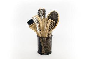 Template with hairdressing gold combs in a stand on a white background. Hair salon accessories.