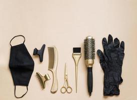 Hairdressing tools on a beige background. Hair salon accessories, scissors, clips, combs, gloves and face mask. photo