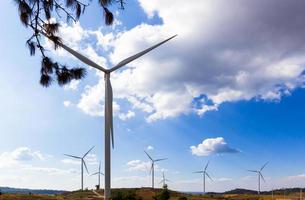 las turbinas eólicas producen electricidad de energía limpia en el fondo del cielo azul y las nubes. foto