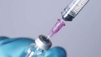 gros plan d'une aiguille d'injection aspirer un médicament transparent dans une seringue, un médicament dans un flacon, prêt pour l'injection de vaccin, l'administration d'un système de sérum, une cure d'approvisionnement en vaccin contre le coronavirus video