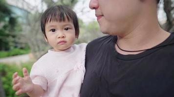 Asian young father holding his pretty baby daughter in his arms, family warmness spending time together at the park, infant young age development, family activity on the weekend taking a walk outdoors video
