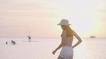 belle fille asiatique portant un chapeau de plage d'été aime regarder le coucher du soleil sur la côte, retraite au coucher du soleil sur la plage de l'île, vacances de vacances tropicales, heure d'or, week-end d'été relaxant, voyage de villégiature