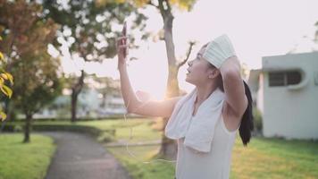 jovem mulher asiática liga para amigos com videochamada móvel se exercitando no parque, aproveite o exercício no parque ao ar livre, experiências de vida saudáveis, tendo comunicação digital online, tecnologia sem fio video