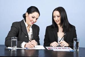 Two business women writing in office photo