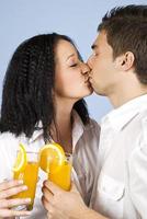 Kissing couple celebrate with fresh orange juice photo