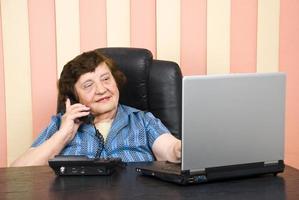 Elderly executive using laptoop and talk by phone photo