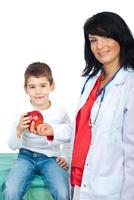 Smiling doctor giving apple to a child photo