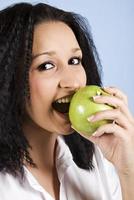 mujer joven muerde una manzana verde foto