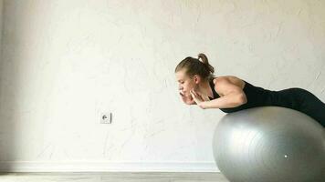 fitness, deportes y estilo de vida saludable. mujer joven haciendo ejercicio en casa con pelota de estabilidad o pelota de fitness. entrenamiento en casa video