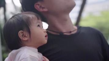 jonge aziatische vader en zijn schattige schattige babymeisje maken een wandeling in het park, onder de schaduw van bomen, kinderopvang voor baby's, familie mix generatie binding, kinderen onschuld nieuwsgierigheid