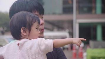 young Asian father holding infant baby girl look around neighborhood parking lot area, child care learning and development, parenting bonding, children innocence, chinese father and daughter video