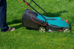 man mows the lawn with a mower on a sunny day photo