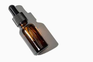 Botella ámbar de aceite esencial con pipeta aislada sobre fondo blanco. copie el espacio