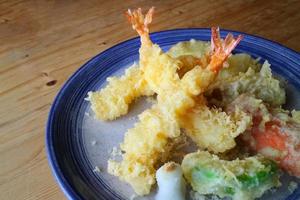 tempura japonesa con verduras frescas fritas y camarones servidos en un plato redondo de cerámica. comida tradicional japonesa foto