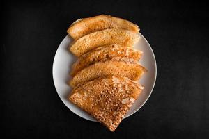 Thin pancakes on a plate on a black background, traditional Russian food. photo