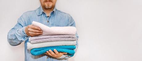 Man is organizing and cleaning the house. A stack of clean terry towels in hand. Storage and housekeeping concept. photo