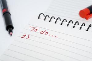 una lista de tareas escrita a mano en un papel blanco con marcador rojo. foto
