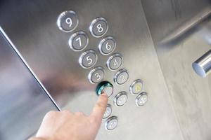 Finger presses button on first floor in elevator photo