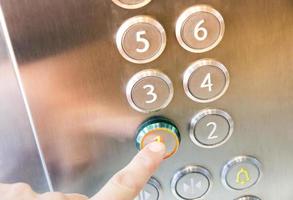 Man's hand causes first floor in metal elevator photo