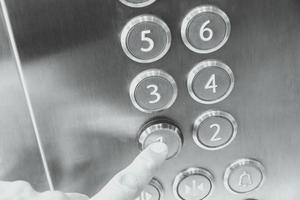 Man's hand causes first floor in metal elevator photo