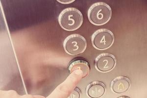 Man's hand causes first floor in metal elevator photo