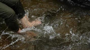 toma tiros lentos usando tus piernas para golpear el agua en la cascada. diviértete jugando en este atractivo natural. video