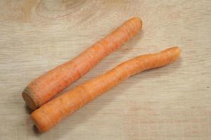 Two orange carrots on a wooden background photo