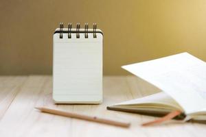 Small note book paper or notepad stand for writing information with pencil and book on wood table photo