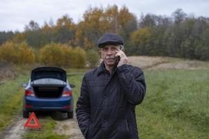 Adult pensioner calls technical assistance on smartphone after his faulty car photo
