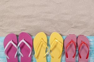 Sand copy space. Sand background top view. Multicolored beach flip flops photo