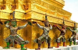 escultura gigante alrededor de la base de la pagoda dorada en wat phra kaew foto