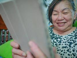 muy felices ancianas asiáticas miran la tableta en su casa