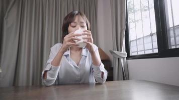 Short hair young asian woman feeling positive happy joyful while drinking hot tea in the morning, confident lady enjoy herself staying at home, online dating, distance relationship, relaxing emotion